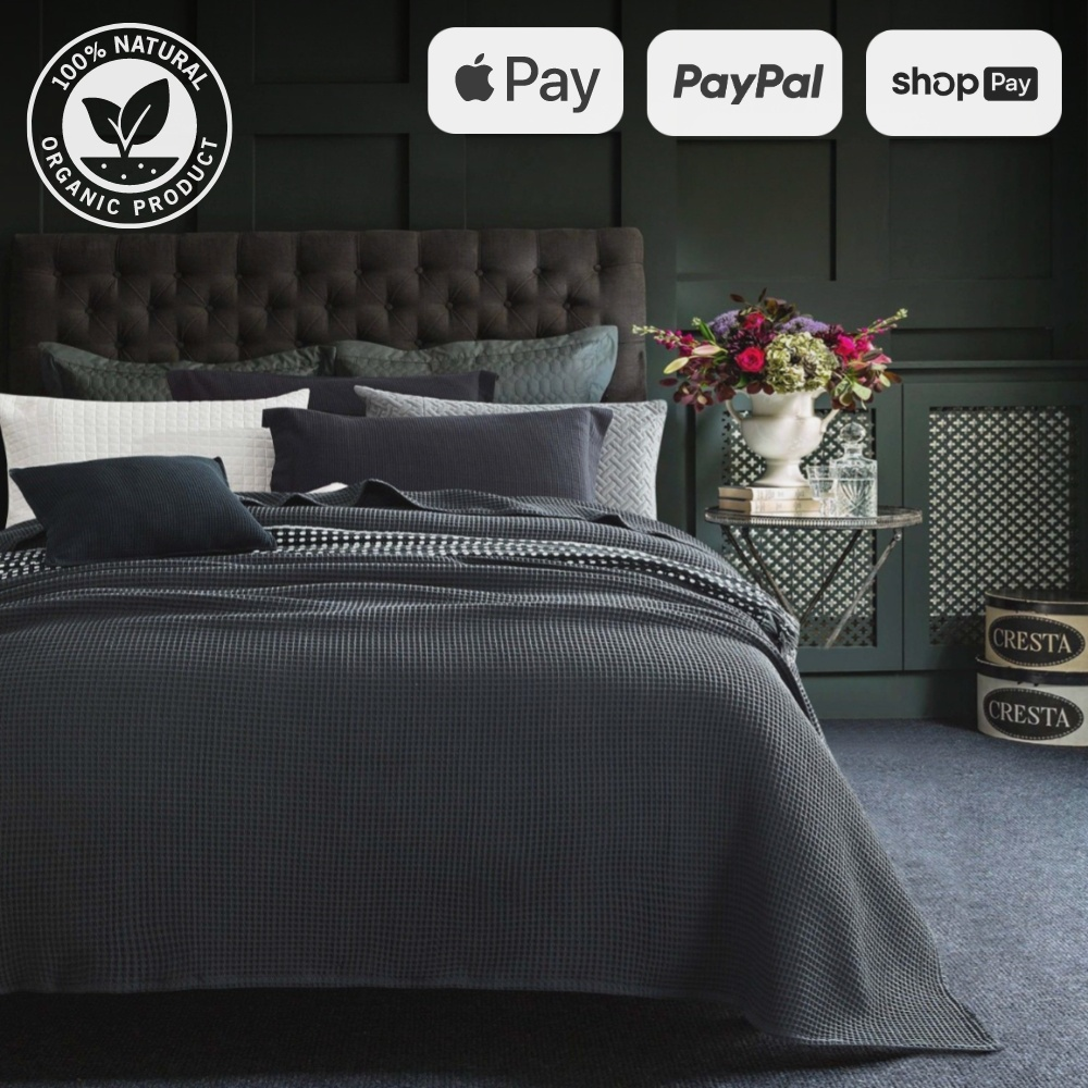 Cozy bedroom with dark gray bamboo waffle throw blanket on bed, elegant decor, and natural organic product certification.