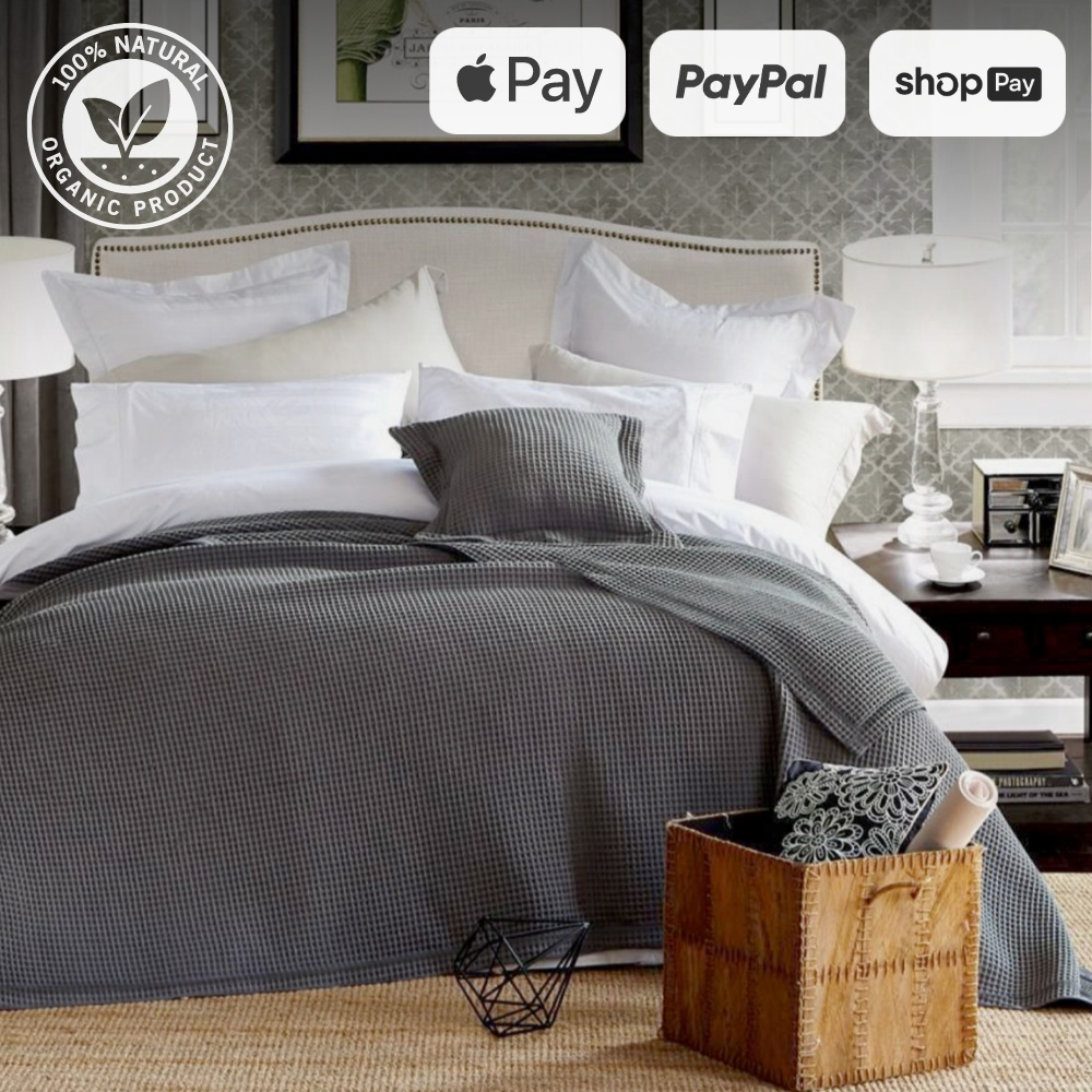 Bamboo waffle throw blanket on a neatly made bed with decorative pillows, showcasing organic product logo and payment options including Apple Pay, PayPal, and Shop Pay.