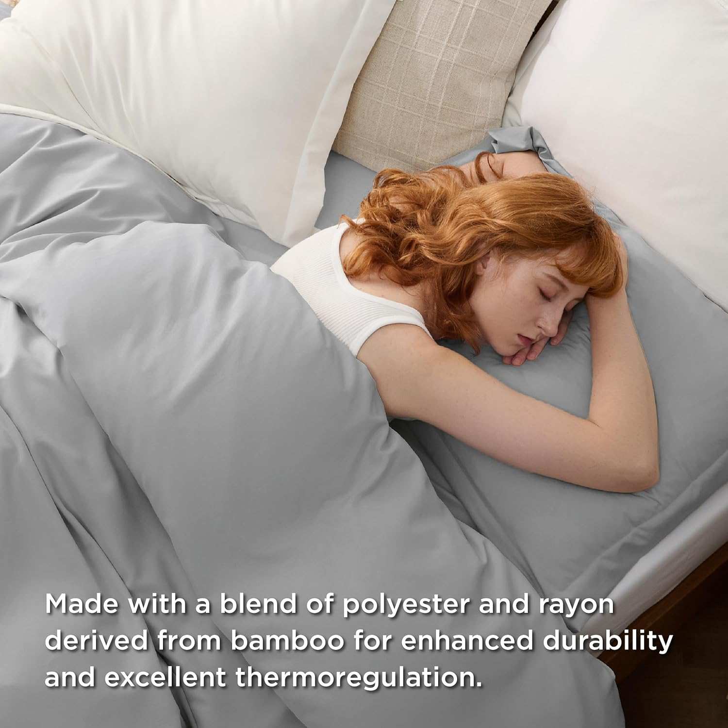 Red-haired woman sleeping under light grey polyester and bamboo blend bedding known for durability and thermoregulation