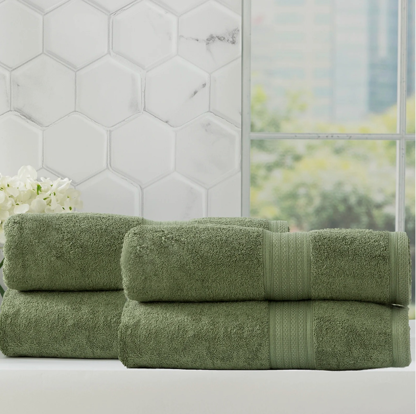 Organic bamboo towels by Adorearth neatly folded, in front of white hexagonal tile backdrop, perfect for eco-friendly bathroom decor.