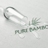 A close-up shot of a water spill on a fabric labeled 'Pure Bamboo,' showcasing the water-resistant properties of Adorearth's eco-friendly bamboo bedding