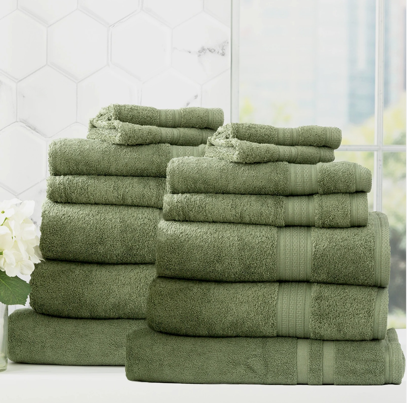 Organic bamboo towels by Adorearth in green, stacked and displayed in a bright, modern bathroom.