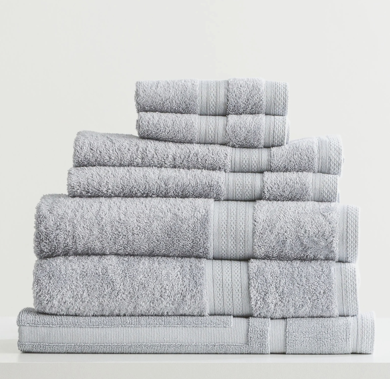 A stack of soft, gray Adorearth™ organic bamboo towels on a white surface